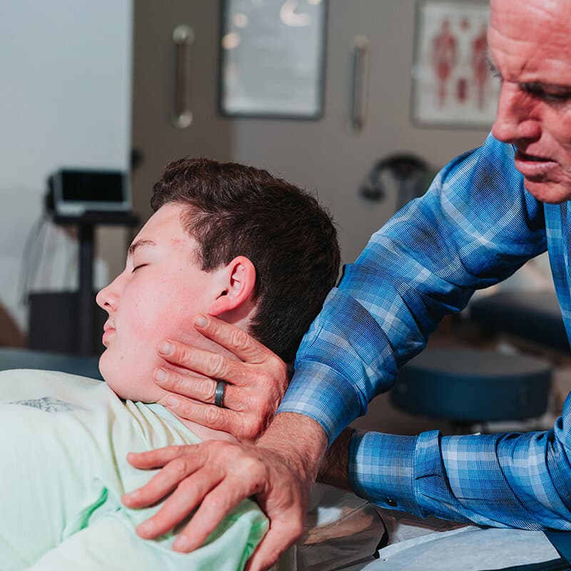 Dr. Foudy performing a gentle cervical adjustment on a younger patient